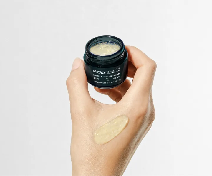 Hand holding a Meltryx Micro Activator jar with a product swatch on the skin
